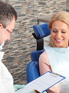 Dentist looking at clipboard while talking to patient