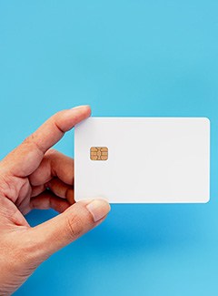 Hand holding credit card against blue background