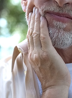 Close-up of man rubbing jaw in pain