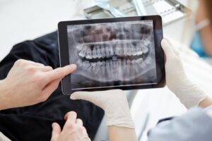 Patient and dentist examining oral x-ray on tablet