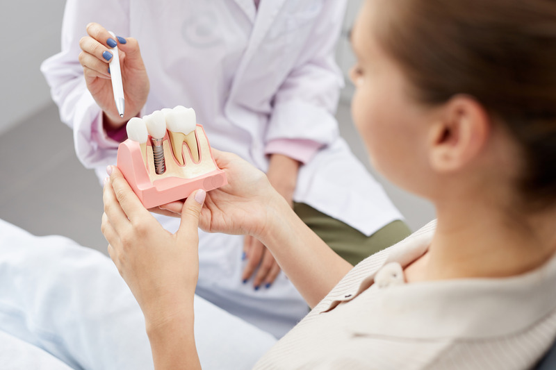 Patient looking at a model of dental implants while dentist explains