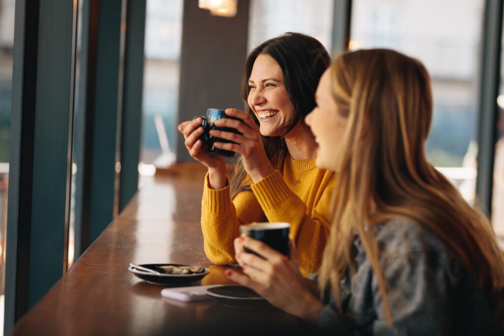 Two friends smiling while drinking coffee